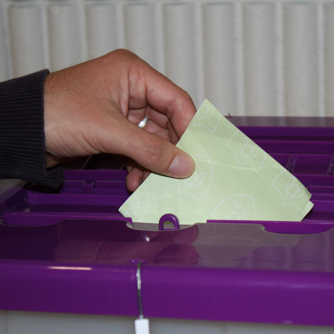 A person puts their ballot into a ballot box during an election.